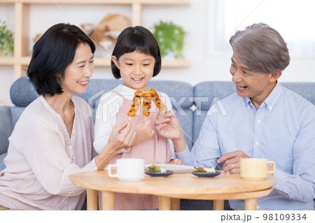 おじいちゃんおばあちゃんと和菓子を食べる女の子 98109334