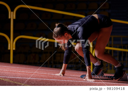 Young sportswoman at the starting blocks before running sprint Young sportswoman at the starting blocks before running sprint 98109418