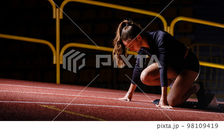 Young sportswoman at the starting blocks before running sprint Young sportswoman at the starting blocks before running sprint 98109419