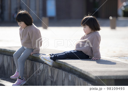 公園のベンチに座っている女の子の姉妹 98109493