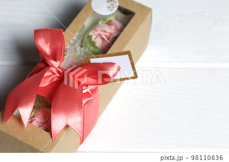 Zephyr handmade in a gift box. Marshmallow in a box tied with a ribbon. Zephyr tulips. On white boards. Close-up. 98110836