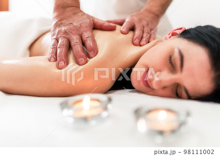 Masseur massaging back and shoulder blades of young woman lying on massage table on white background. Concept of massage spa treatments Masseur massaging back and shoulder blades of young woman lying on massage table on white background. Concept of massage spa treatments 98111002