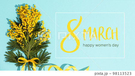 Spring mimosa branches with a yellow ribbon flat lay on blue background 98113523
