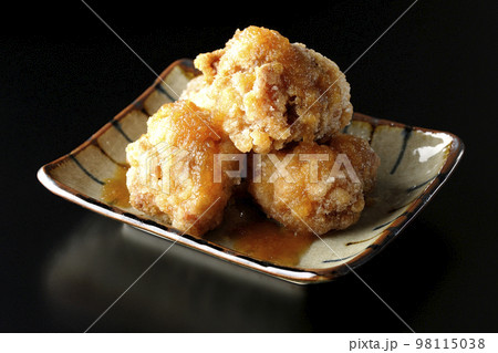 鶏の竜田揚げにおろしポン酢かけを黒背景で撮影 鶏の竜田揚げにおろしポン酢かけを黒背景で撮影 98115038
