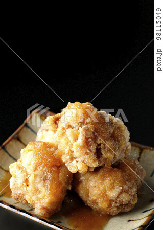 鶏の竜田揚げにおろしポン酢かけを黒背景で撮影 鶏の竜田揚げにおろしポン酢かけを黒背景で撮影 98115049