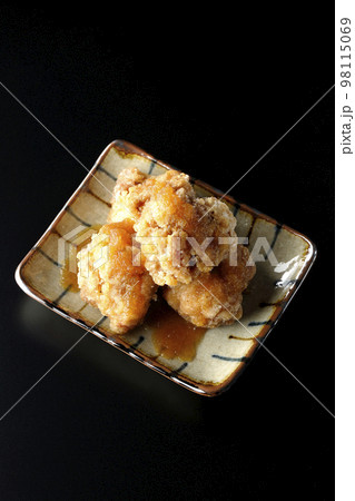 鶏の竜田揚げにおろしポン酢かけを黒背景で俯瞰撮影 98115069