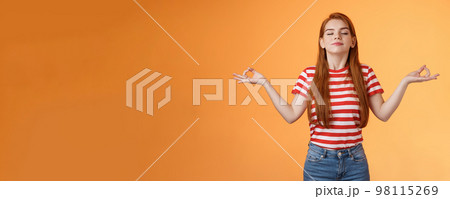 Girl listening relaxing podcast meditating indoors, breath fresh air, close eyes smiling peaceful delighted, stand orange background, chill carefree, enjoy practive yoga, relieve from stress 98115269