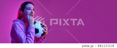 Tense feelings. Portrait of young emotive girl posing with football ball background in neon light. Banner, flyer. Concept of emotions, youth, lifestyle Tense feelings. Portrait of young emotive girl posing with football ball background in neon light. Banner, flyer. Concept of emotions, youth, lifestyle 98115318