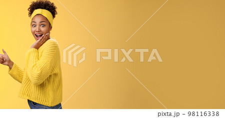 Profile studio shot amused impressed speechless cute stylish shopping girl drop jaw amazed widen eyes turning camera surprised cover open mouth palm pointing left index finger show cool promo 98116338