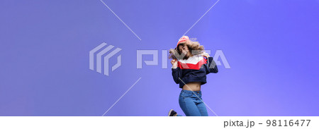 Girl jumping from happiness and delight feeling carefree close eyes and smiling broadly enjoying moment having fun raising hands being dreamy and playful over blue background Girl jumping from happiness and delight feeling carefree close eyes and smiling broadly enjoying moment having fun raising hands being dreamy and playful over blue background 98116477