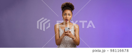Shocked upset african-american woman in glittering stylish expensive dress drop jaw cringing disappointed receive terrible upsetting message holding smartphone look concerned blue background Shocked upset african-american woman in glittering stylish expensive dress drop jaw cringing disappointed receive terrible upsetting message holding smartphone look concerned blue background 98116678
