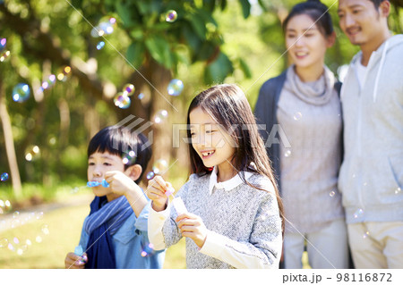 little asian boy and girl blowing bubbles outdoors 98116872