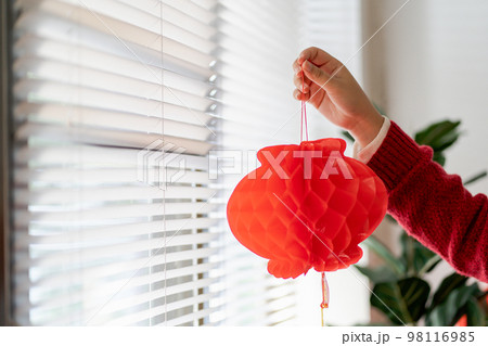 Asian Woman holding red Chinese new year lantern while decorated flat putting traditional pendant to the Chinese New Year Celebrations for good luck. chinese word means blessing. 98116985