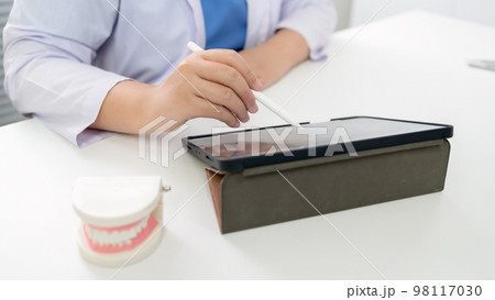 Dentist at dental clinic White healthy tooth with Dental model in oral surgeons discussing jaw x-ray on tablet medicine healthcare oral surgery concept. 98117030