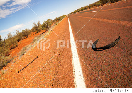 バーストしたタイヤ片が転がる道路 98117433