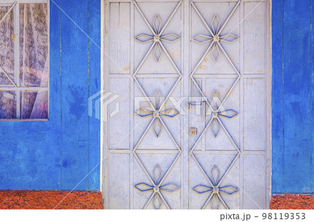 Rustic old metal door with textured adobe wall facade in Cusco, Peru 98119353