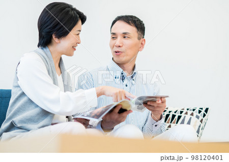 リビングで雑誌を見るミドルの夫婦 リビングで雑誌を見るミドルの夫婦 98120401