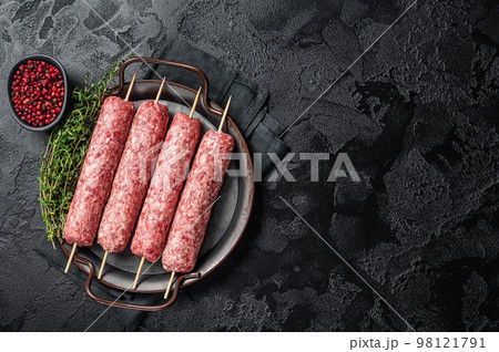 Raw Turkish Urfa kebab skewers in steel tray with herbs. Black background. Top view. Copy space Raw Turkish Urfa kebab skewers in steel tray with herbs. Black background. Top view. Copy space 98121791