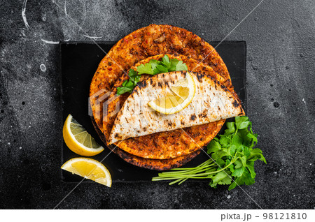 Lahmacun traditional Turkish pizza and wraps with salad on marble board with spices. Black background. Top view 98121810