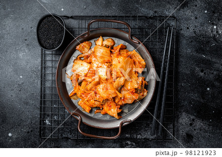 Chinese cabbage kimchi in black dish, Korean cuisine. Black background. Top view Chinese cabbage kimchi in black dish, Korean cuisine. Black background. Top view 98121923