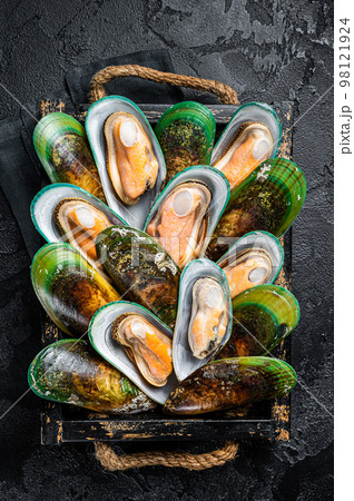 Boiled Green mussels with herbs in a wooden tray. Black background. Top view Boiled Green mussels with herbs in a wooden tray. Black background. Top view 98121924