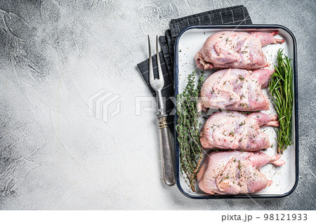 Raw quail meat with spices, garlic and herbs ready to cooking in baking dish. White background. Top view. Copy space 98121933