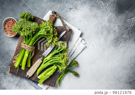Fresh bunch of Broccolini sprouts on cutting board ready for cookining. White background. Top view. Copy space 98121976