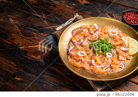 Italian Salmon carpaccio with onion and arugula served on a plate. Wooden background. Top view. Copy space Italian Salmon carpaccio with onion and arugula served on a plate. Wooden background. Top view. Copy space 98122006