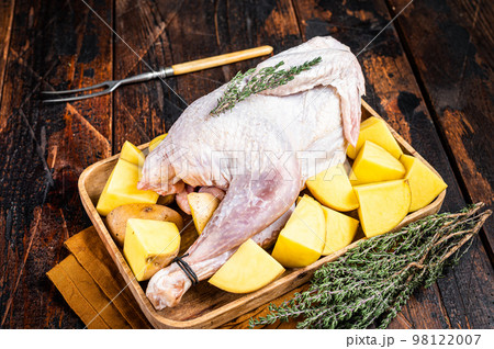 Fresh Raw Guineafowl, guinea fowl with potato, game bird. Wooden background. Top view 98122007