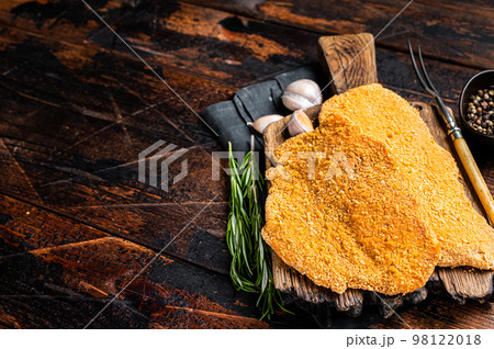 Uncooked Wiener schnitzel in breadcrumbs, raw pork meat. Wooden background. Top view. Copy space Uncooked Wiener schnitzel in breadcrumbs, raw pork meat. Wooden background. Top view. Copy space 98122018