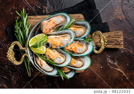 Steamed cooked Green mussels with herbs and spices in a skillet. Dark background. Top view 98122035
