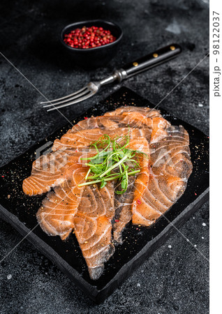 Salmon carpaccio with microgreens on marble board. Black background. Top view Salmon carpaccio with microgreens on marble board. Black background. Top view 98122037
