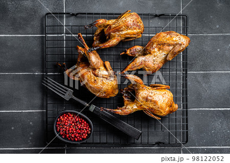 Grilled whole quails with herbs and spices. Black background. Top view Grilled whole quails with herbs and spices. Black background. Top view 98122052