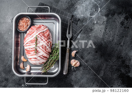 Cooking raw meatloaf with ground beef meat and bacon in steel tray, fresh meat loaf. Black background. Top view. Copy space Cooking raw meatloaf with ground beef meat and bacon in steel tray, fresh meat loaf. Black background. Top view. Copy space 98122160