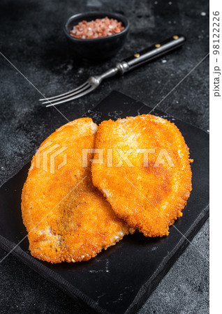 Fried breaded tilapia fillets on a marble board. Black background. Top view Fried breaded tilapia fillets on a marble board. Black background. Top view 98122226