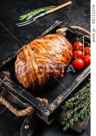 Roast bacon wrapped meatloaf, meat loaf in a tray with herbs. Black background. Top view 98122249