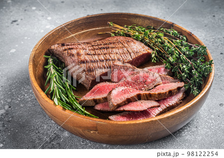 Grilled sliced Skirt Steak on a plate with herbs. Gray background. Top view Grilled sliced Skirt Steak on a plate with herbs. Gray background. Top view 98122254