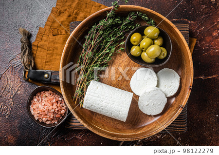 Soft Goat cheese chevre in a plate with thyme and olives. Dark background. Top view 98122279