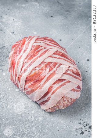 Classic raw meatloaf with ground beef meat and bacon, uncooked meat loaf. Gray background. Top view Classic raw meatloaf with ground beef meat and bacon, uncooked meat loaf. Gray background. Top view 98122357