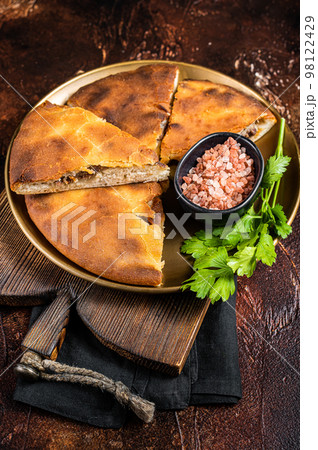 Traditional Ossetian pie sliced on a plate. Dark background. Top view 98122429