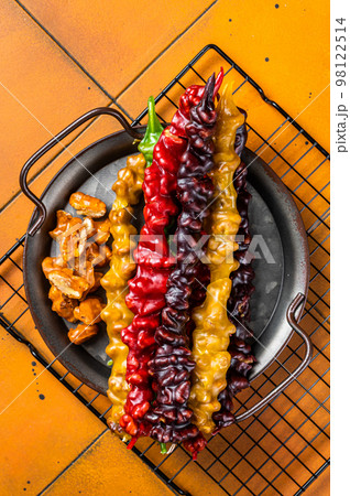 National Georgian sweets Churchkhela with walnut, hazelnuts. Orange background. Top view National Georgian sweets Churchkhela with walnut, hazelnuts. Orange background. Top view 98122514
