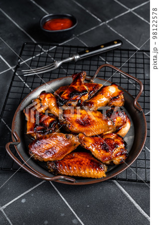 BBQ chicken wings in dip Barbecue sauce. Black background. Top view BBQ chicken wings in dip Barbecue sauce. Black background. Top view 98122578