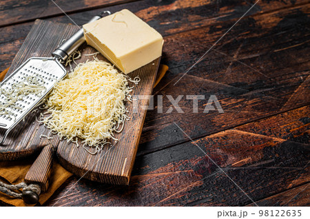 Piece of semi hard cheese and grated cheese with grater. Wooden background. Top view. copy space 98122635