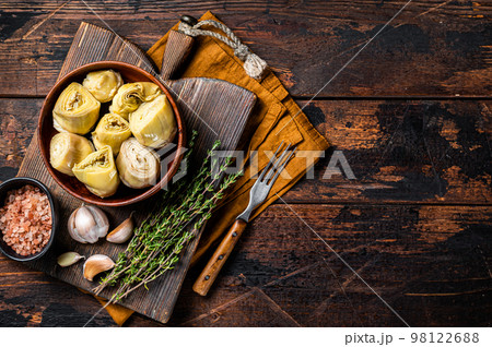 Appetizer Artichoke hearts pickled in olive oil with herbs and spices Wooden background. Top view. Copy space Appetizer Artichoke hearts pickled in olive oil with herbs and spices Wooden background. Top view. Copy space 98122688