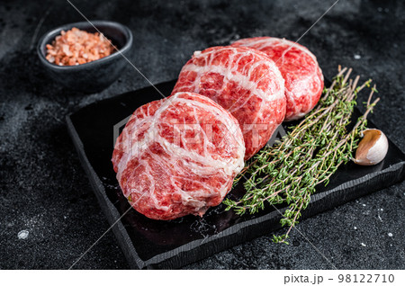 Raw Atriaux cutlets, ground pork wrapped in caul fat, swiss sausage. Black background. Top view 98122710