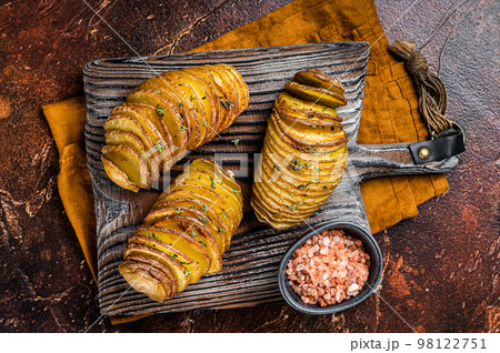 Roasted Hasselback Potato with Fresh thyme and rosemary. Dark background. Top view 98122751