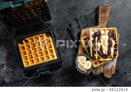 Breakfast with Belgian waffles, banana and Chocolate Syrup. Black background. Top view Breakfast with Belgian waffles, banana and Chocolate Syrup. Black background. Top view 98122819