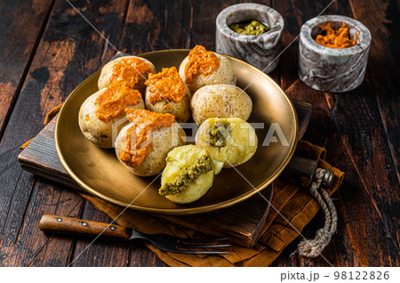 Canary Islands dish Papas Arrugadas wrinkly salty potatoes with and Mojo picon red spicy sauce. Wooden background. Top view 98122826