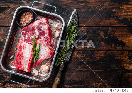 Raw beef Short Ribs in steel tray with rosemary. Wooden background. Top view. Copy space 98122847