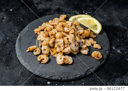 Roast peeled Shrimps prawns with garlic and olive oil, Cocktail shrimps. Black background. top view Roast peeled Shrimps prawns with garlic and olive oil, Cocktail shrimps. Black background. top view 98122877